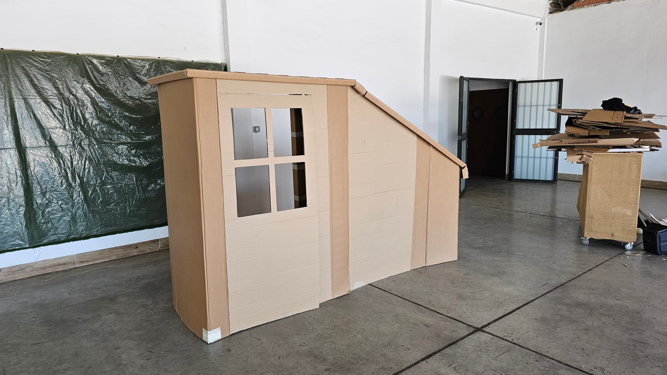 La estructura levantada en cartón, con puerta, ventana y tejadillo inclinado, antes de pintar.