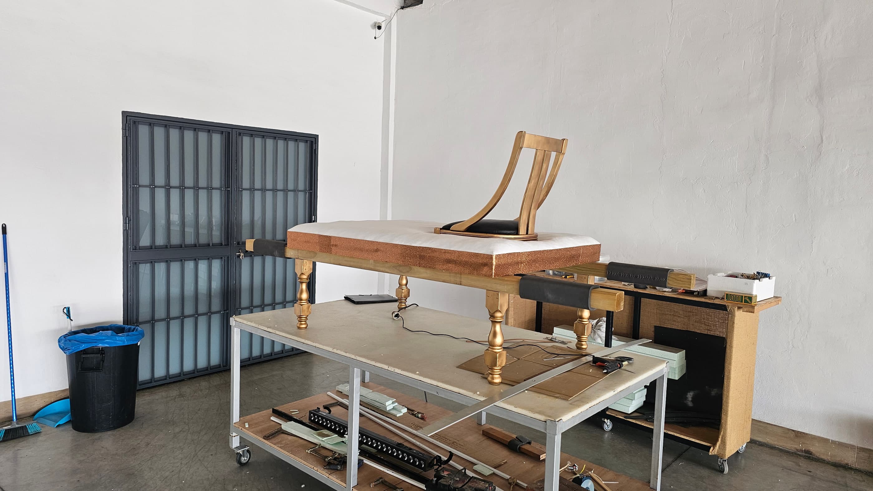 El trono en construcción en el taller: la base con patas doradas y el respaldo dorado antes de tapizar del todo.